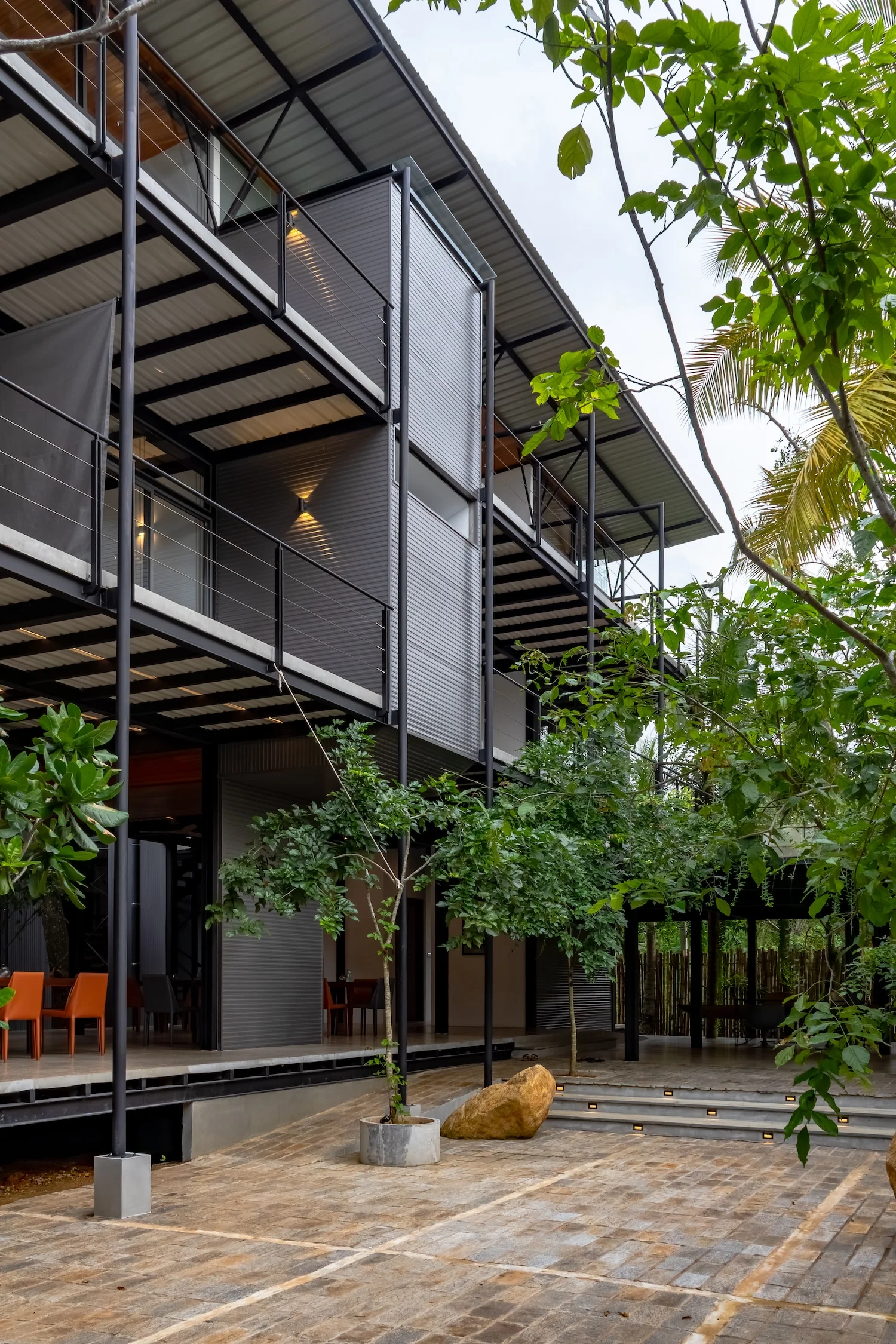 Dusk exterior portrait of BlackRoots framed by palms and warm architectural lighting