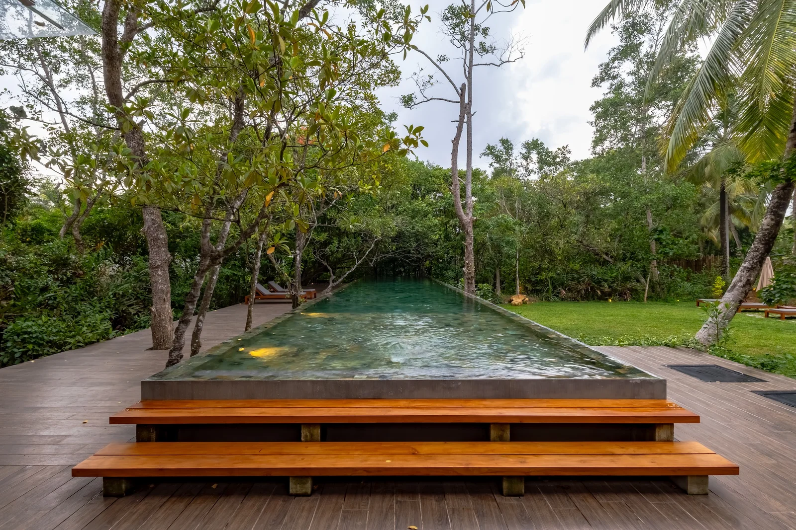 Infinity pool waterline reflecting tropical foliage and soft daylight
